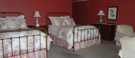 A bedroom with two beds, a chair, a dresser, and a nightstand.