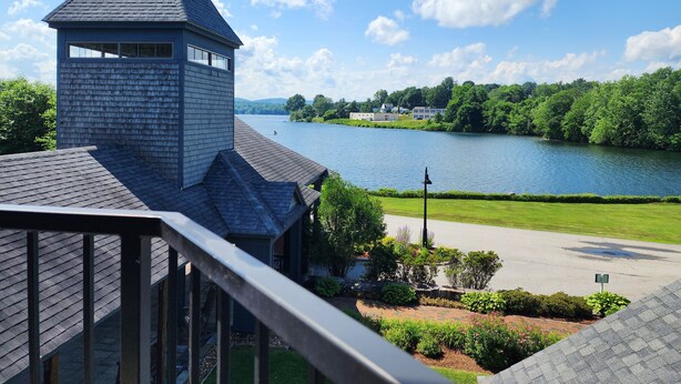 A building with a tower and a view of a lake and greenery. - Lake Opechee Inn and Spa (Laconia)