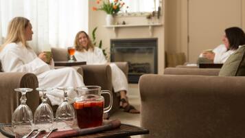 A living room with three sofas, a fireplace, and a tray with glasses and a pitcher of tea.