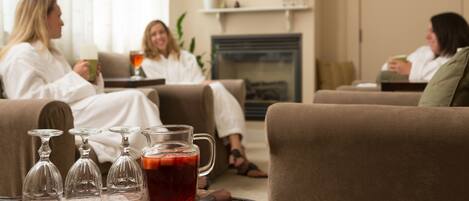 A living room with three sofas, a fireplace, and a tray with glasses and a pitcher of tea.