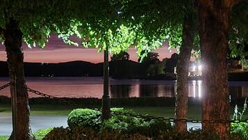 A nighttime view of a lake with trees and a chain-link fence.