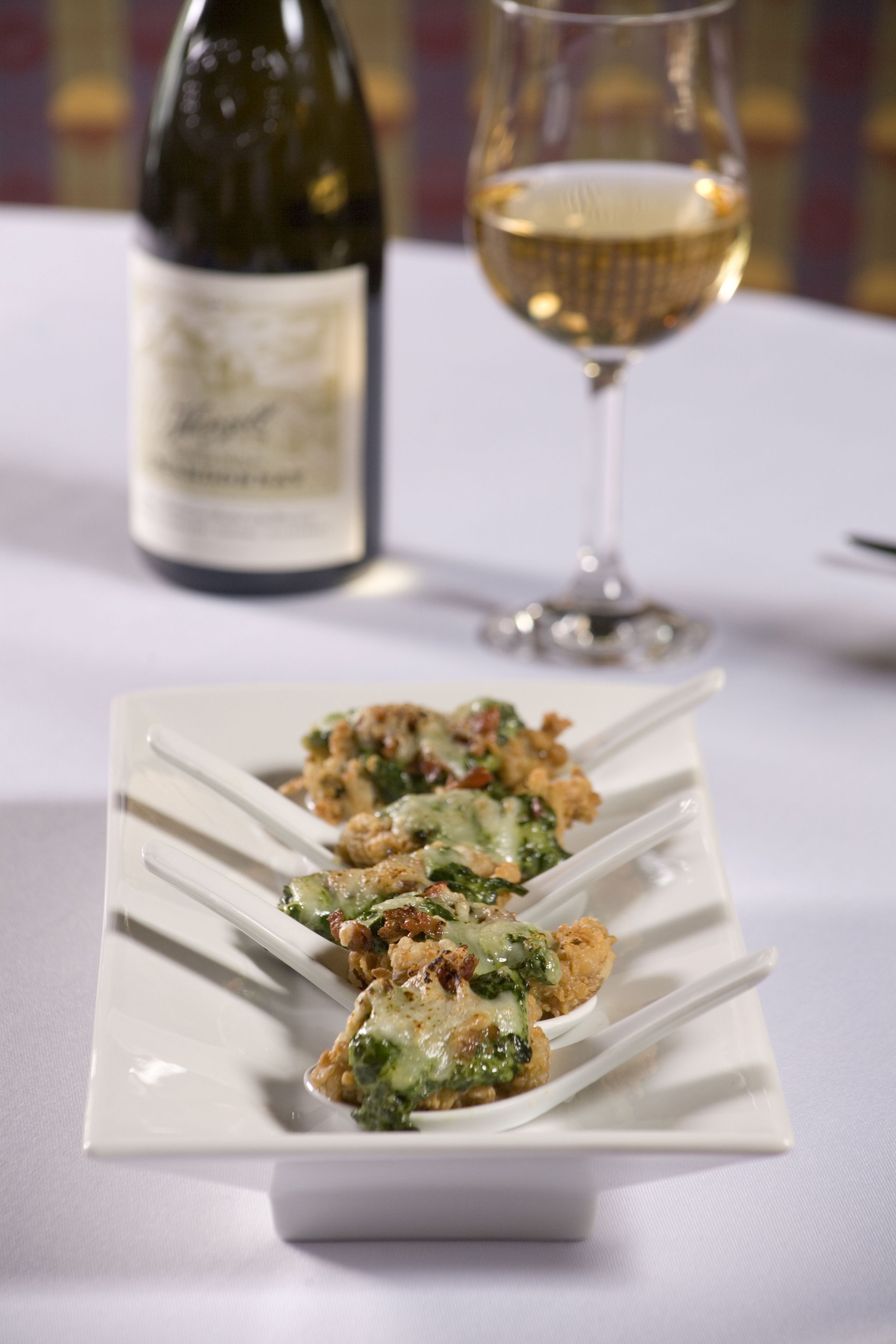 A white plate with food and a wine bottle in the background.