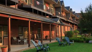 A multi-story hotel with a covered patio area, outdoor seating, and a well-maintained lawn.