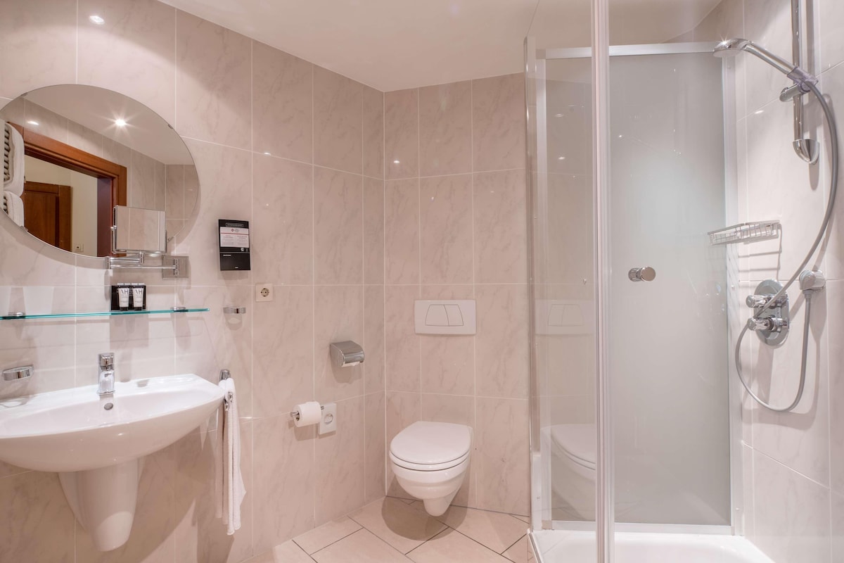 A modern bathroom with a glass-enclosed shower, a white sink, and a toilet.