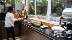 A buffet area with various food items and a person serving. - Best Western Plus Grand Hotel Victor Hugo (Luxembourg City)