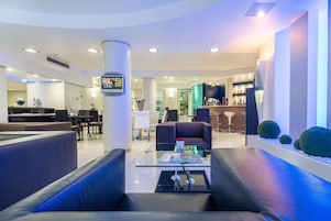 Un moderno vestíbulo de hotel con asientos de cuero, una zona de bar y una pantalla de televisión.