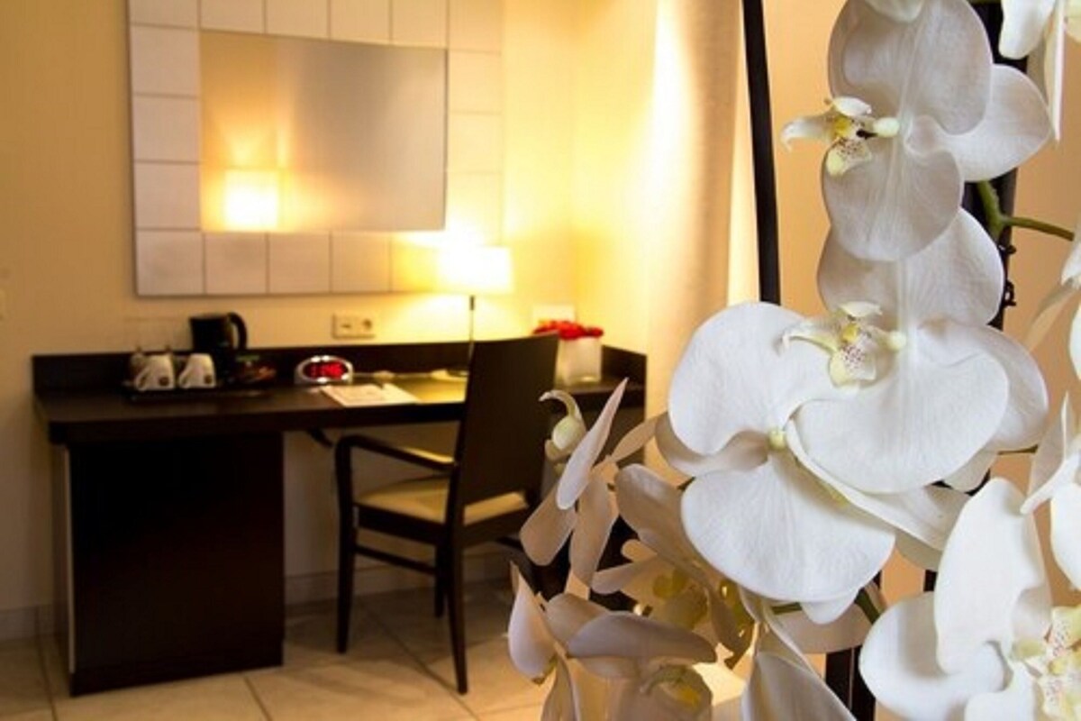 A hotel room with a desk, chair, and a large mirror.