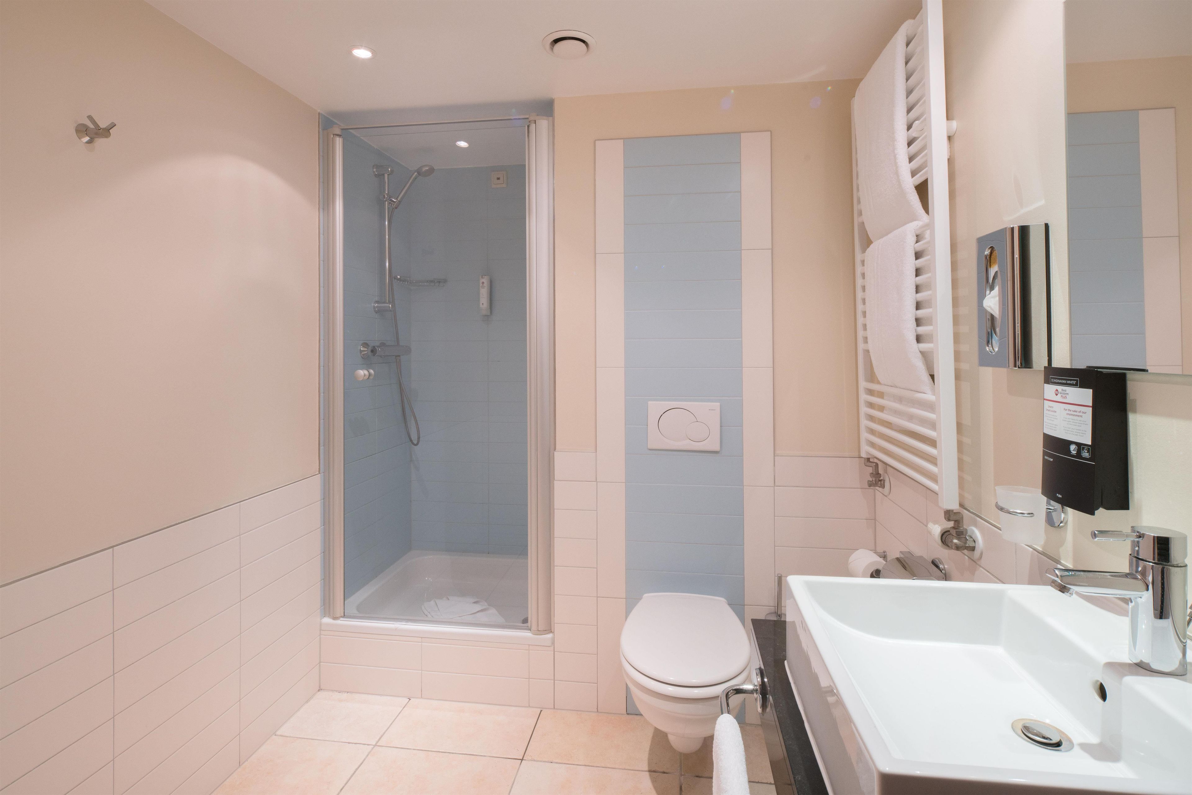 Un baño moderno con ducha de vidrio, inodoro y lavamanos con espejo.