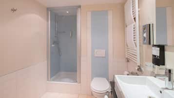 Un baño moderno con ducha de vidrio, inodoro y lavamanos con espejo.
