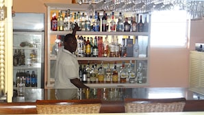 Uma área de bar com prateleiras cheias de garrafas de bebidas e copos.