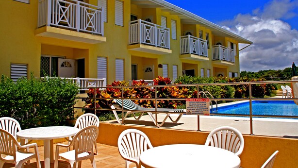 Um hotel com varandas, piscina e área externa para sentar.