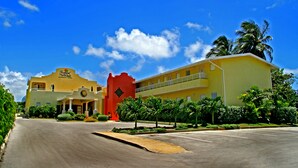 Um hotel com fachada amarela, torre vermelha e céu azul límpido.