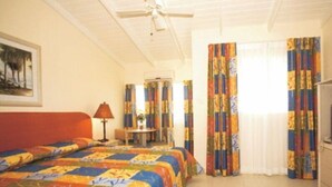 Quarto de hotel com cama, escrivaninha, cadeira, abajur e cortinas.