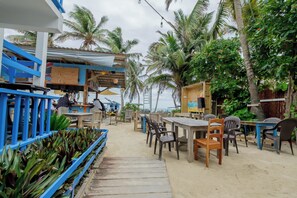 An outdoor seating area with tables and chairs, surrounded by palm trees and plants. - Seven Seas Resort (San Pedro)