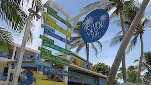 A colorful signpost with various event times and a 'Seven Seas' sign. - Seven Seas Resort (San Pedro)