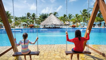 Alberca al aire libre, sombrillas en la alberca y camastros