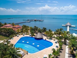 Un resort con una amplia piscina, palmeras y vistas al océano.