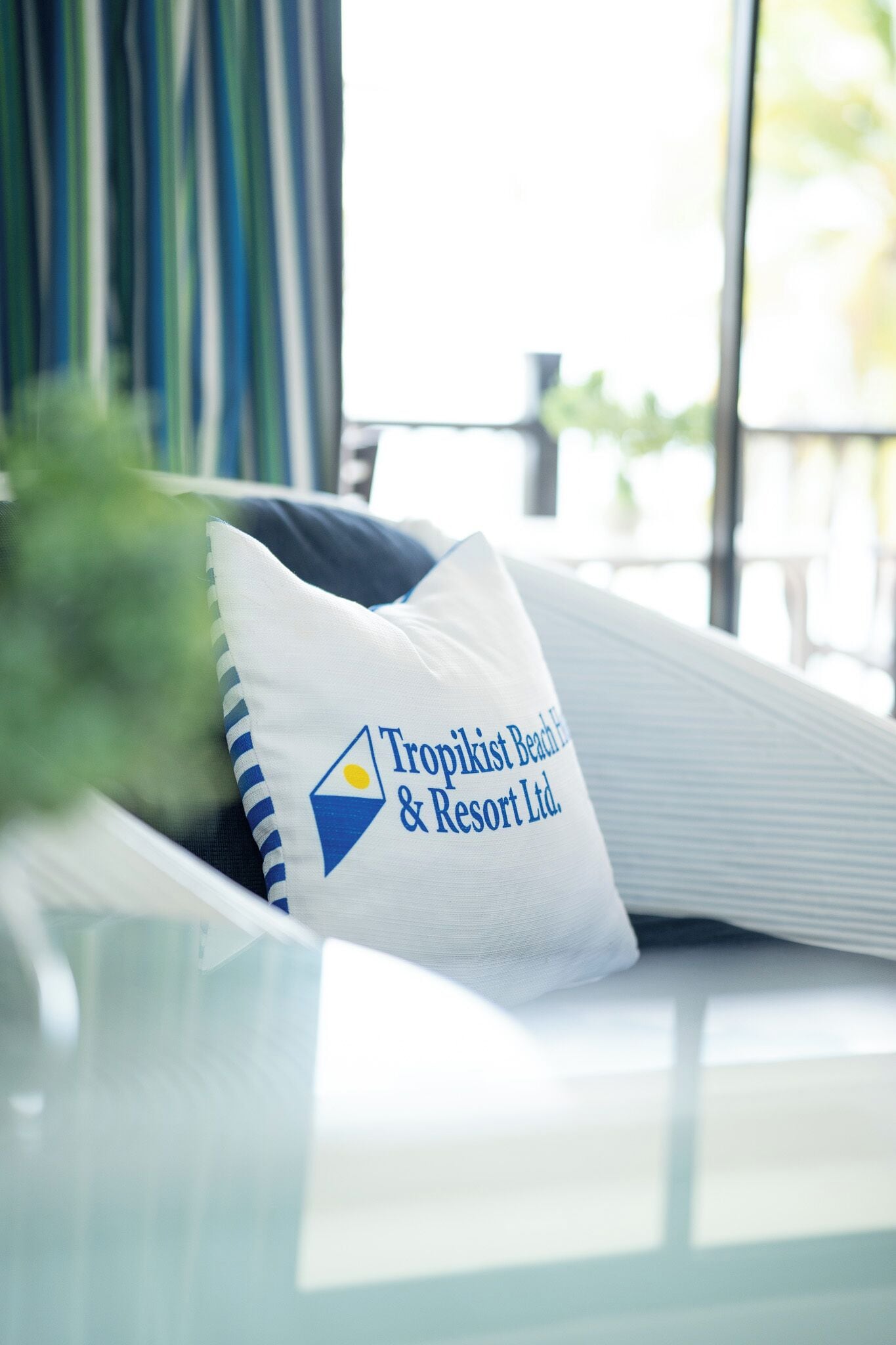 A pillow with the logo of Tropikist Beach & Resort Ltd. on a white bedspread.