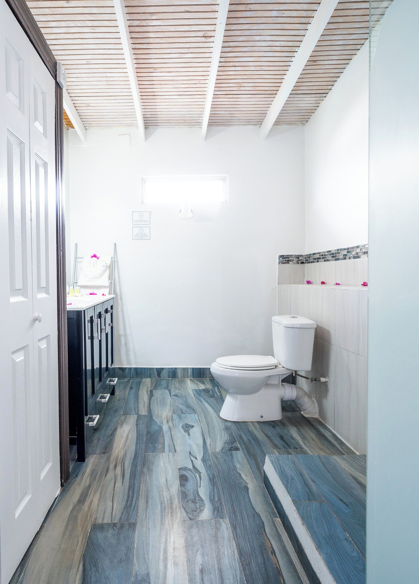 A bathroom with a white toilet, a shower area, and a vanity with a mirror.