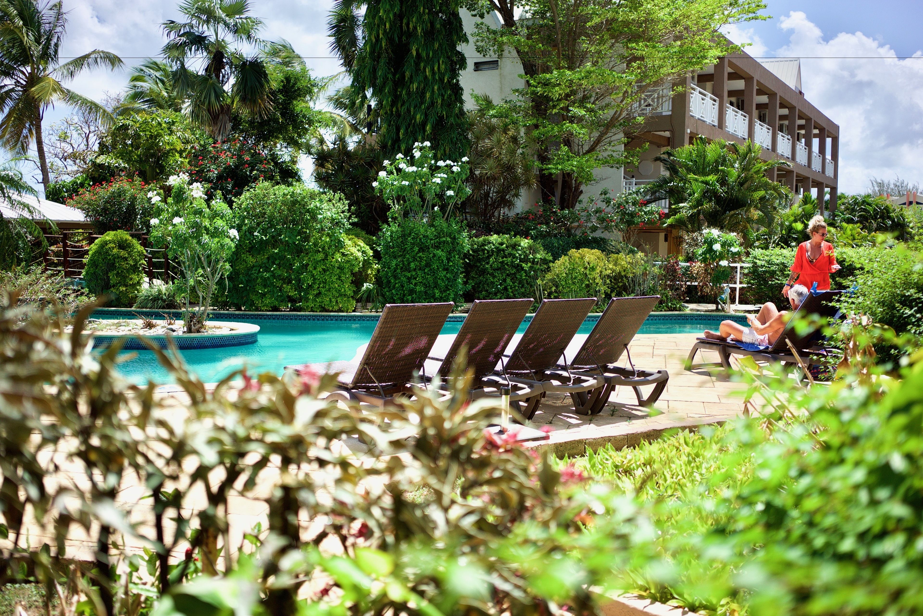 A poolside area with lounge chairs, a fountain, and lush greenery.