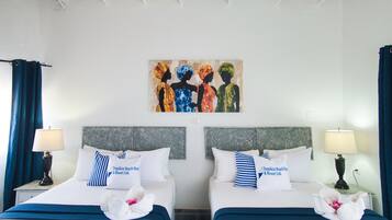 Quarto de hotel com duas camas, cada uma com cabeceira, almofadas e uma toalha sobre a cama. Há um quadro na parede acima das camas.