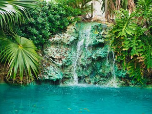 A waterfall cascading into a clear pool surrounded by lush greenery. - Tropikist Beach Hotel & Resort (Crown Point)