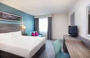 A hotel room with a large bed, a desk with a television, a chair, and a window with curtains. - Leonardo Hotel Plymouth (Plymouth)