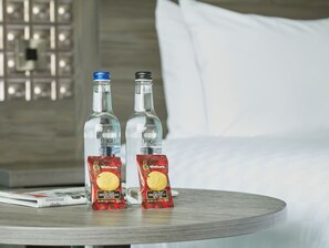 Two bottles of Decanta Natural Mineral Water and two packets of Walkers Pure Better Shortbread Round on a round table in a hotel room. - Leonardo Hotel Plymouth (Plymouth)
