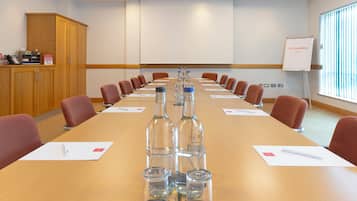 A conference room with a long table, chairs, a whiteboard, and a cabinet.
