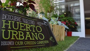 A sign for a green garden with text in Spanish and English.