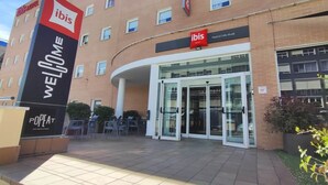 An ibis hotel entrance with a 'WELCOME' sign, glass doors, and outdoor seating area. - ibis Madrid Calle Alcala (Madrid)