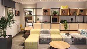 A modern living room with a sofa set, a wooden coffee table, and a bookshelf with various items. - ibis Madrid Calle Alcala (Madrid)