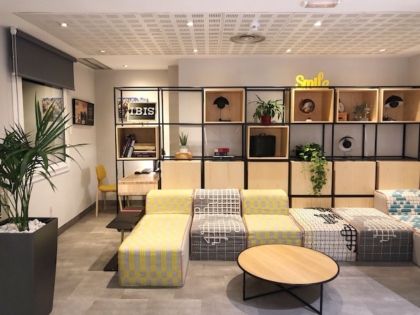 Un salon moderne comprenant un ensemble de canapés, une table basse en bois et une bibliothèque contenant divers objets.