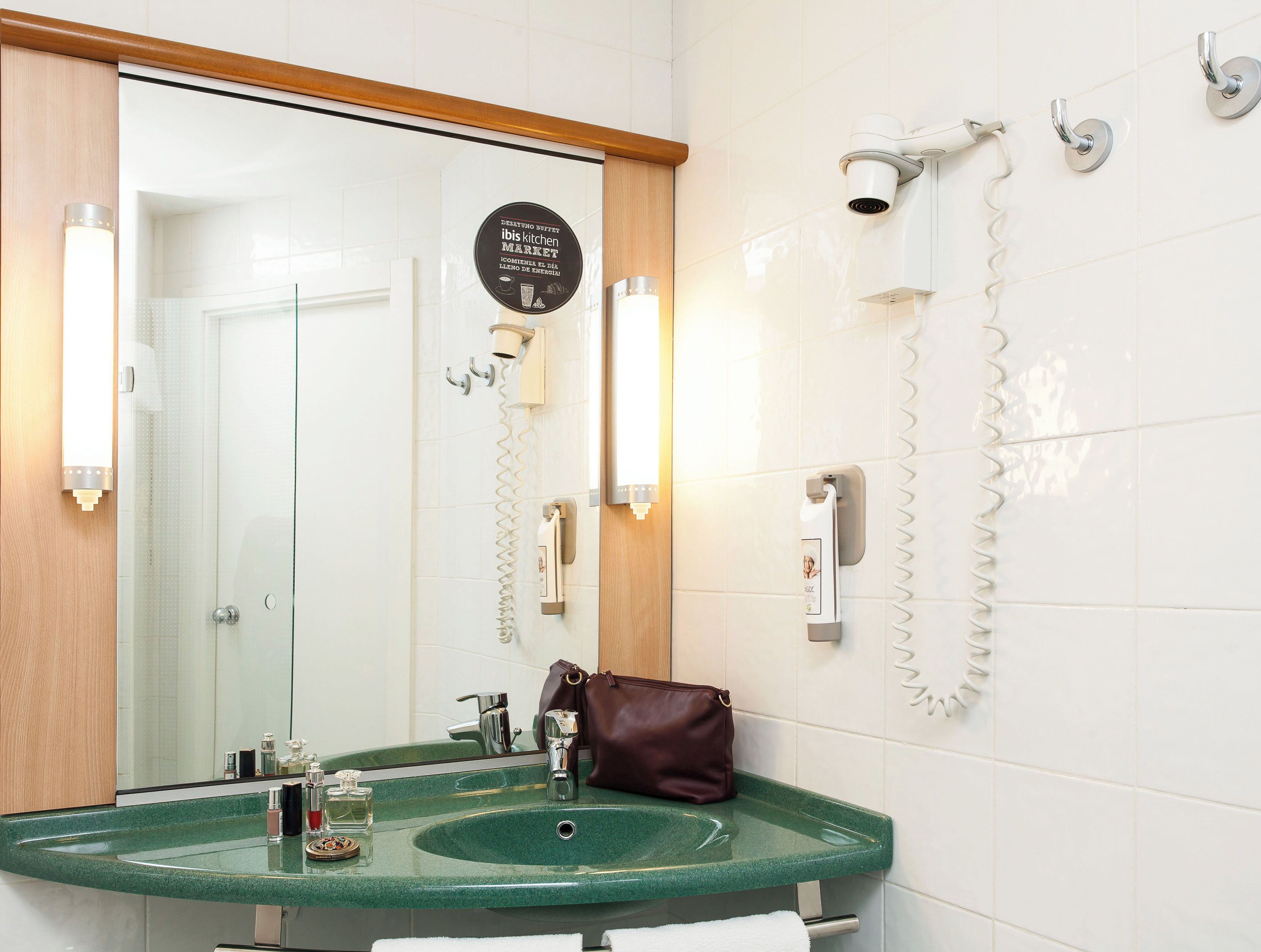 A bathroom with a green sink, a mirror, a hairdryer, and a towel rack.