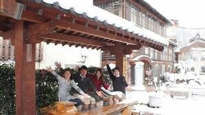 A wooden bench with stone bases, set in a snowy outdoor area with traditional architecture in the background. - Hotel Mets Fukushima (Fukushima)