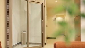 A hotel corridor with a sliding glass door, a trash bin, and a framed picture on the wall. - Hotel Mets Fukushima (Fukushima)
