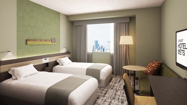 A hotel room with two beds, a desk, a chair, a lamp, a window with a city view, and a wall-mounted artwork. - Hotel Mets Fukushima (Fukushima)