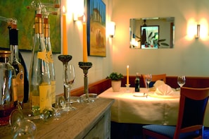 A dining table set with wine glasses and bottles, a candle, and a mirror on the wall. - AKZENT Hotel Albert (Dorsten)