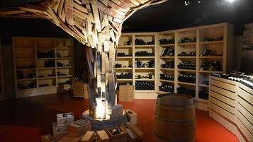 Una bodega con estanterías de madera y barriles, y repisas con botellas de vino.