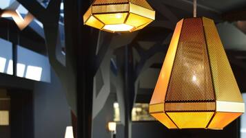 Un interior moderno con lámparas colgantes hexagonales, muebles oscuros y una alfombra estampada.