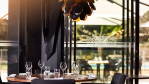 A dining area with a round table set for four, surrounded by dark chairs.