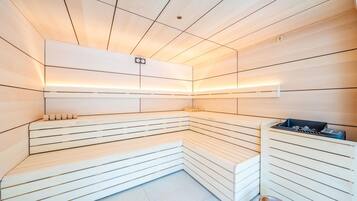 A sauna with wooden benches and a bench with a trash bin.