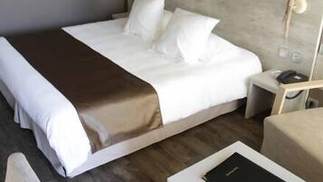 A hotel room with a bed, bedside tables, a chair, and a small table with a book.