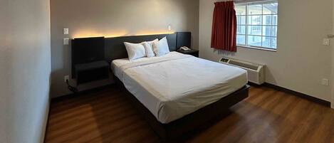 Habitación de hotel con cama, mesita de noche y ventana con cortinas.