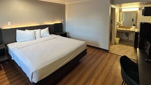 Una camera d'albergo con un letto grande, una scrivania e un bagno visibile attraverso una porta aperta.