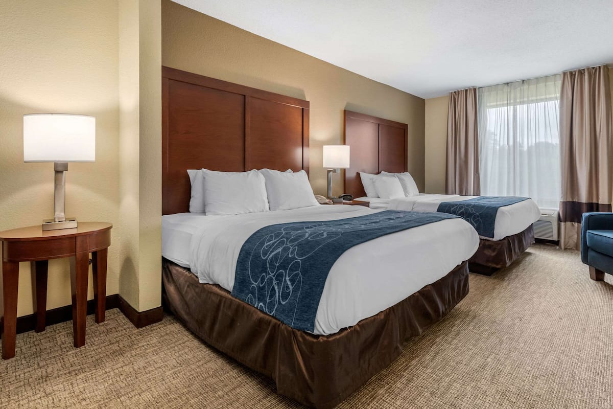 Een hotelkamer met twee bedden, een bureau en een stoel.