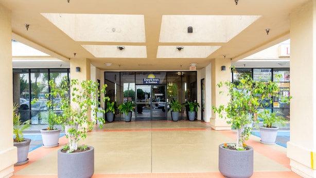 A hotel entrance with a flat roof, potted plants, and a sign for Days Inn & Suites.