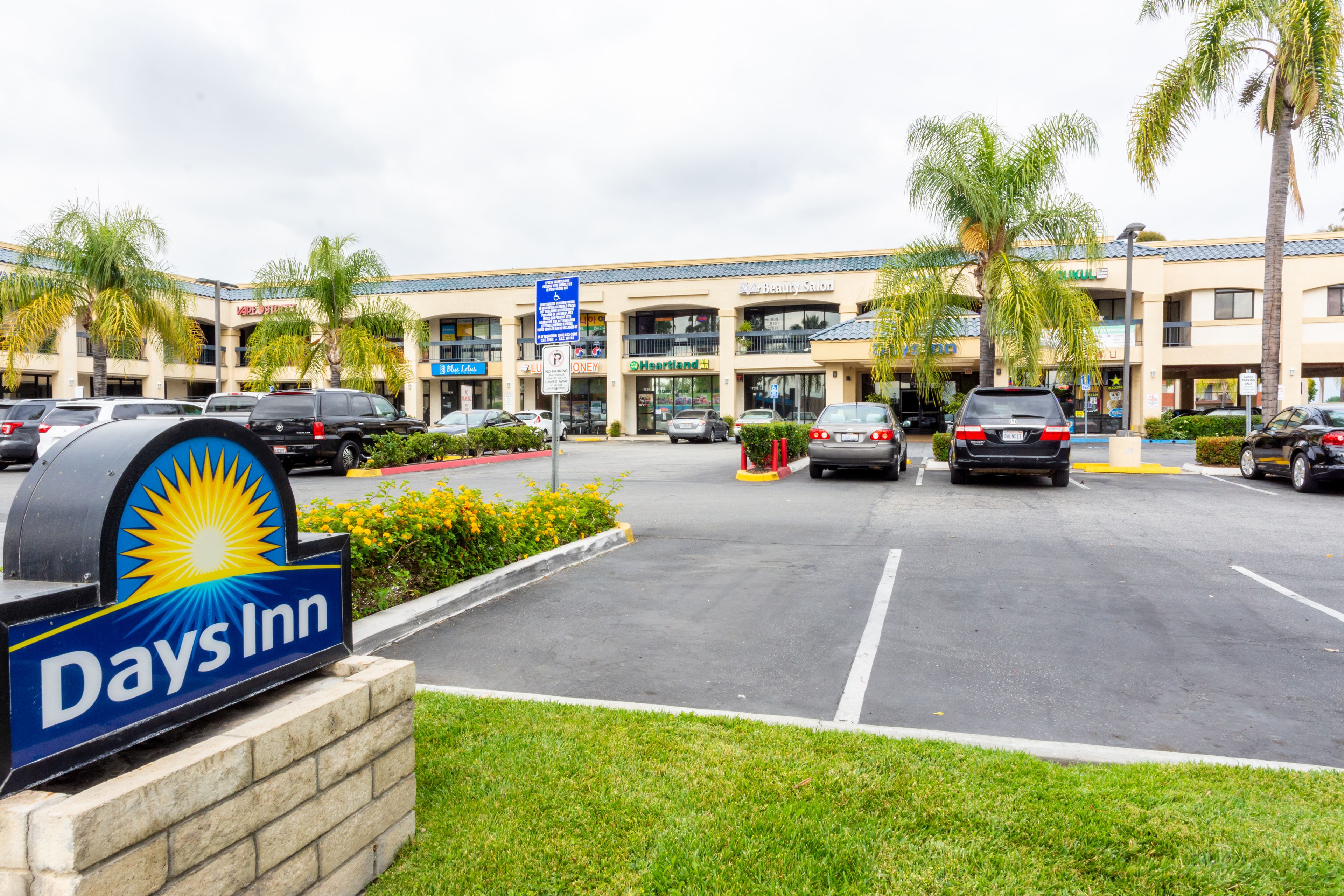 Een Days Inn hotel met een parkeerplaats, palmbomen en een gebouw met meerdere etages.