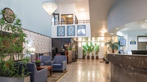 A spacious lobby with a reception desk, seating area, and decorative plants.