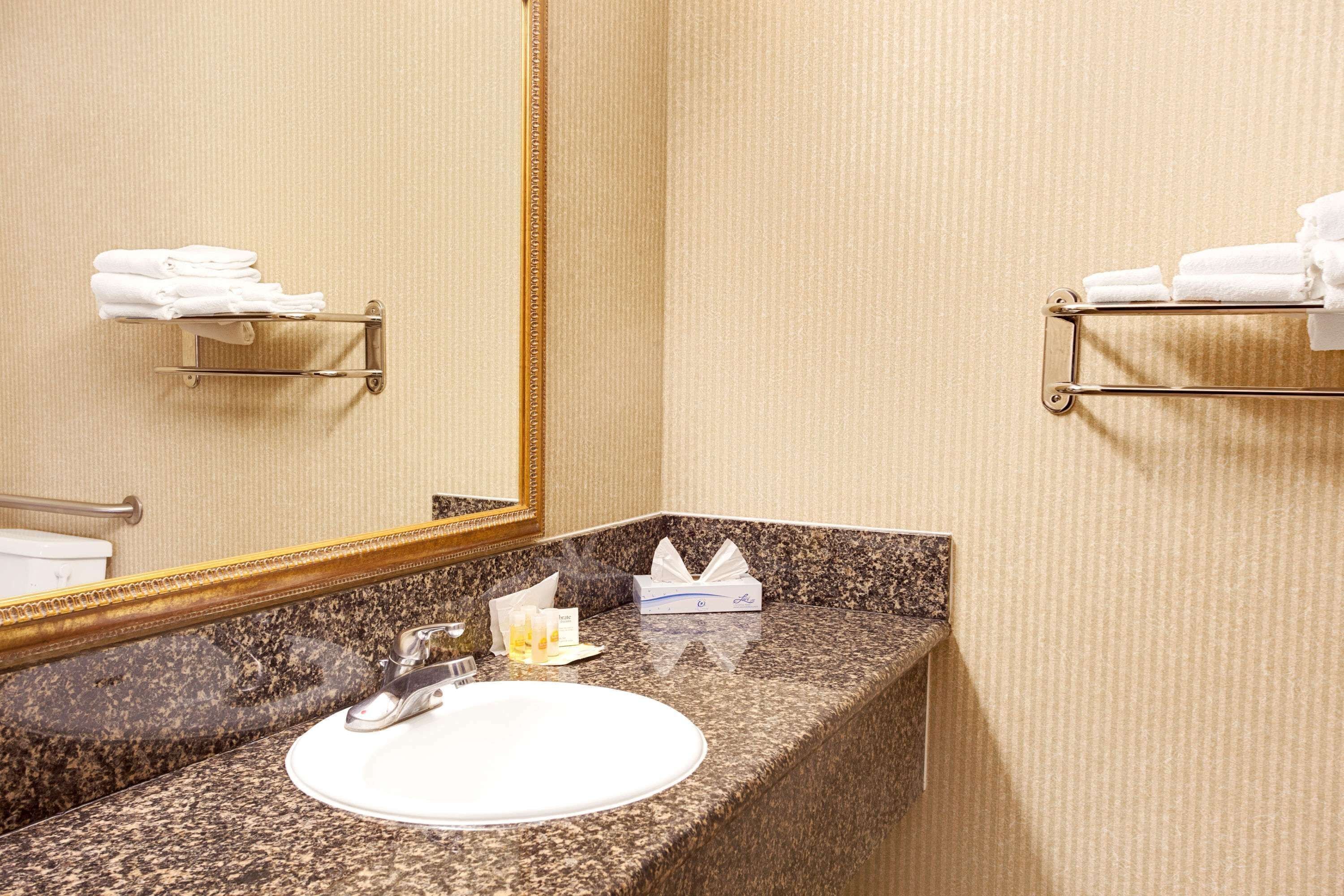 Une salle de bain avec un comptoir en granit, un lavabo, un miroir et des porte-serviettes.